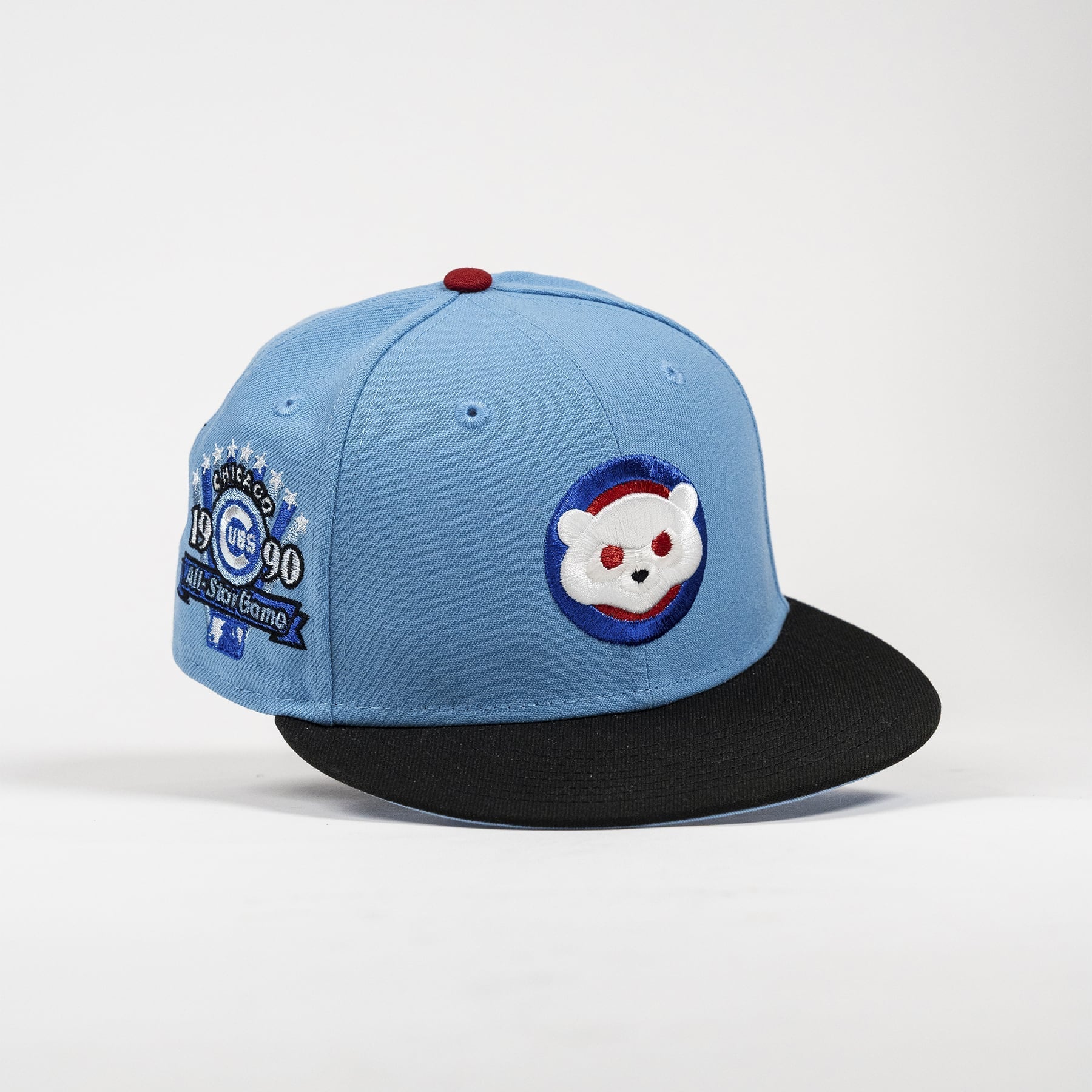 A light blue and black baseball cap featuring a Chicago Cubs 1990 World Series patch on the side and a white bear patch on the front, set against a plain light gray background.