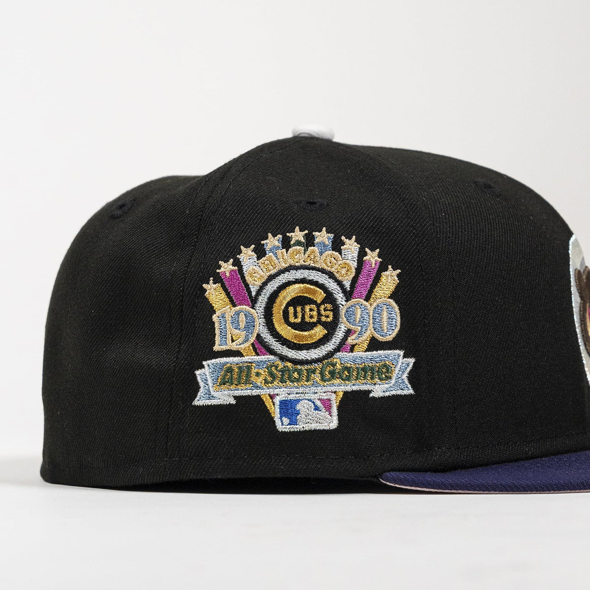 A black baseball cap featuring a large embroidered Chicago Cubs 1990 All-Star Game patch on the front, with a dark purple brim visible on the right side, set against a plain white background.