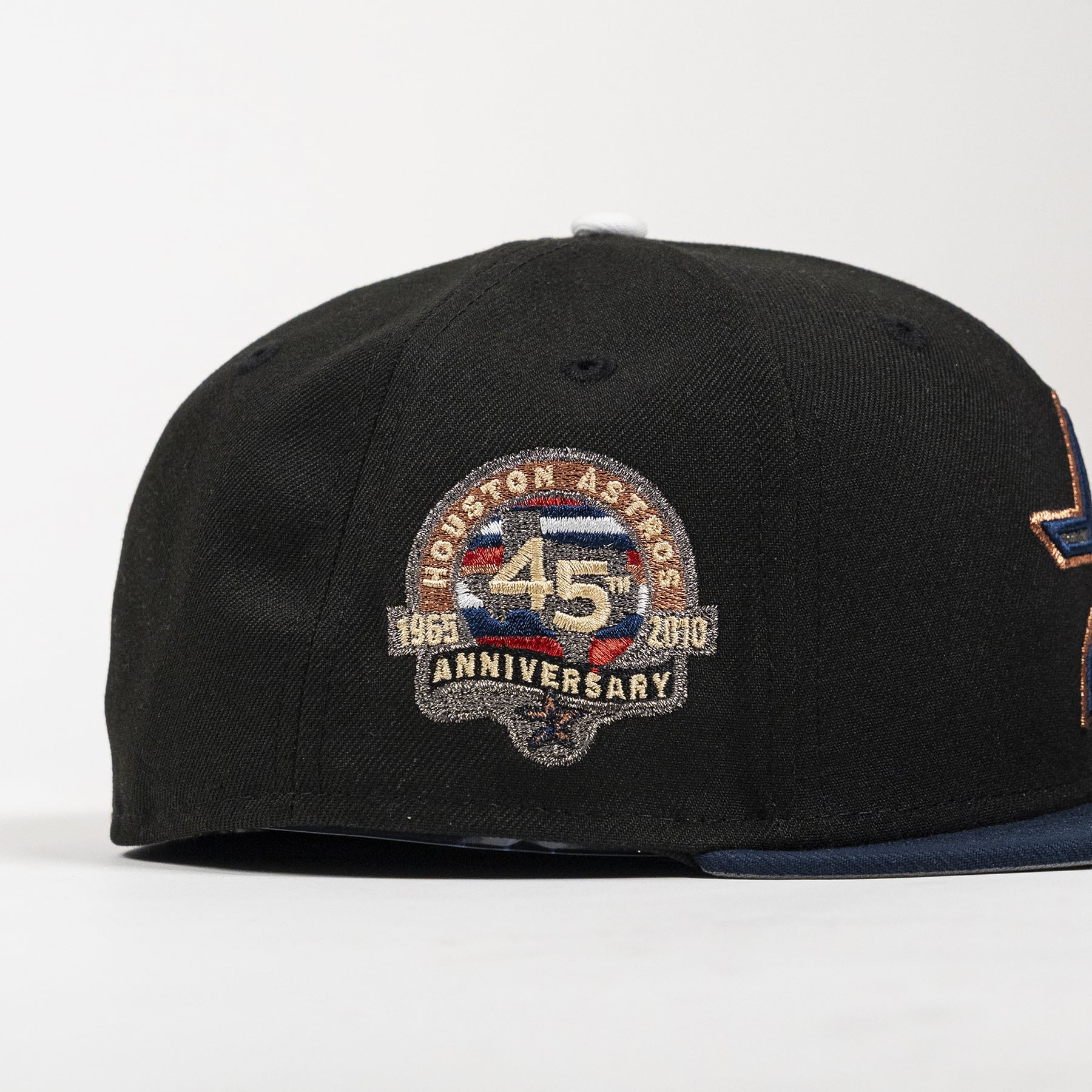 A black Houston Astros baseball cap featuring a prominent embroidered 45th Anniversary patch on the front, with a navy blue flat brim and a partial side patch visible.