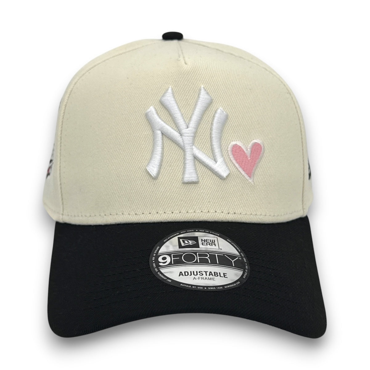 Beige and black cap with New York Yankees logo and pink heart on a white background