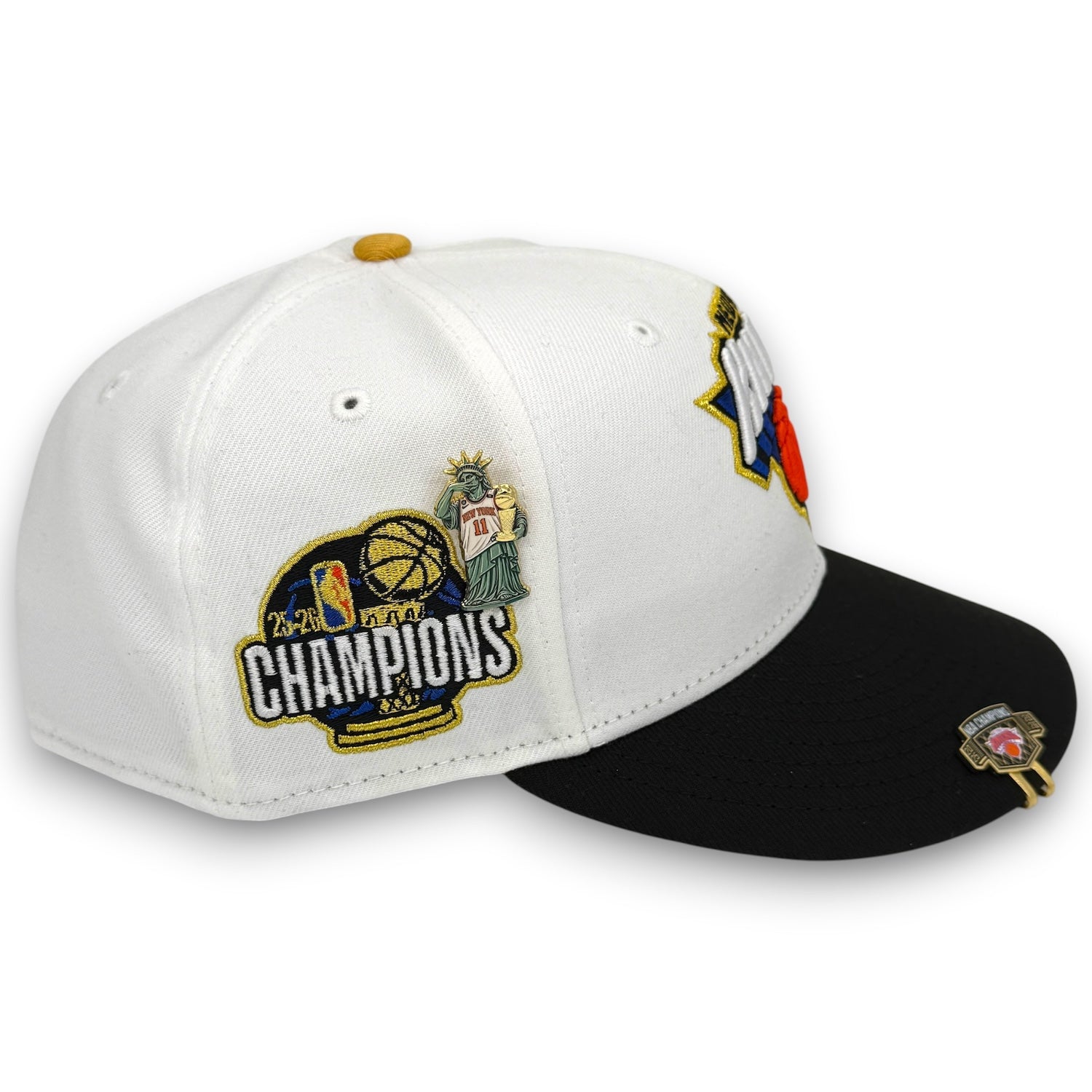 A white and black snapback cap featuring a 2024 NBA Champions patch on the front, a Texas state patch on the side, and a small gold pin on the brim, shown against a plain white background.