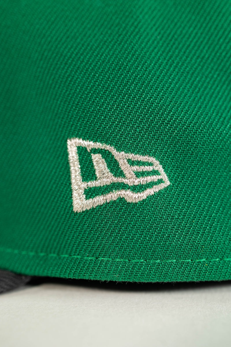 Close-up of a bright green woven cap with a white embroidered New Era flag logo on the side.