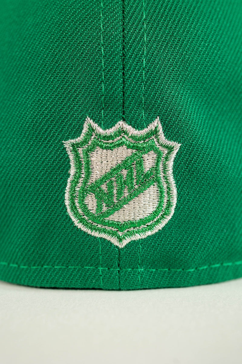Close-up of a green knit cap featuring an embroidered white and green NHL shield logo on the front.