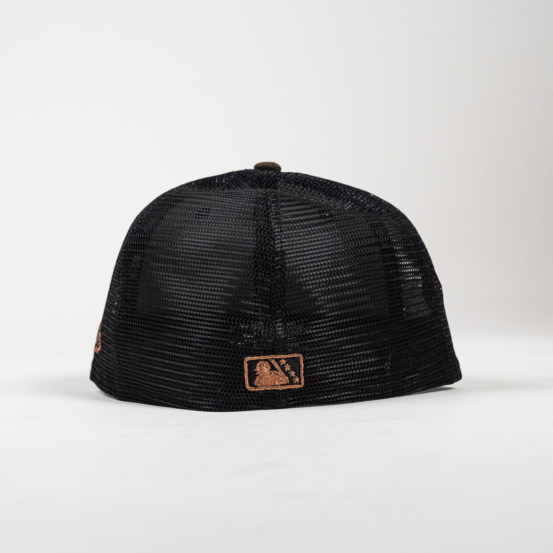 A black mesh-back baseball cap with a brown leather patch on the front brim featuring the MLB logo, photographed against a clean white studio background.